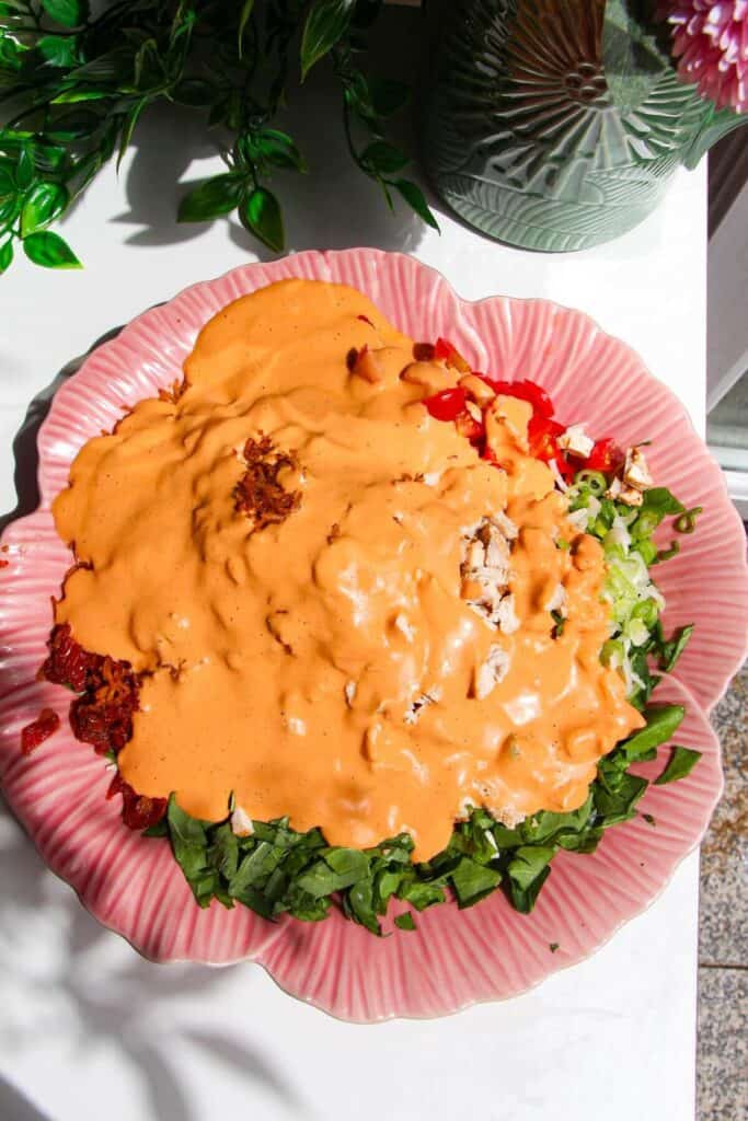 'Marry Me' dressing poured over salad ingredients in a pink bowl.