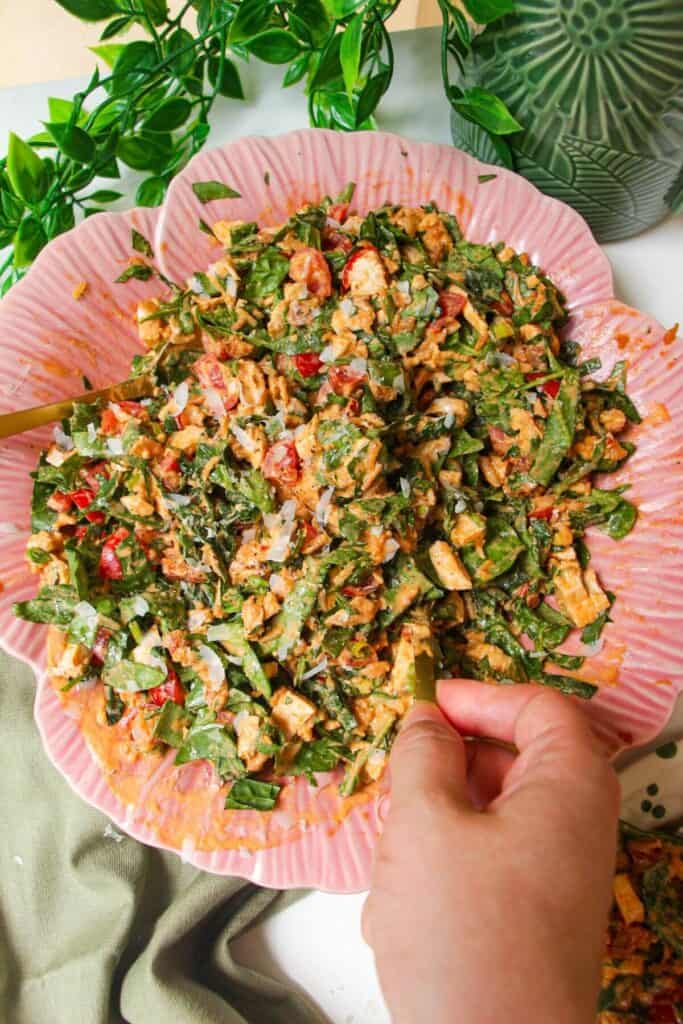 Mixing 'Marry Me' chicken crispy rice salad in a pink flower bowl.