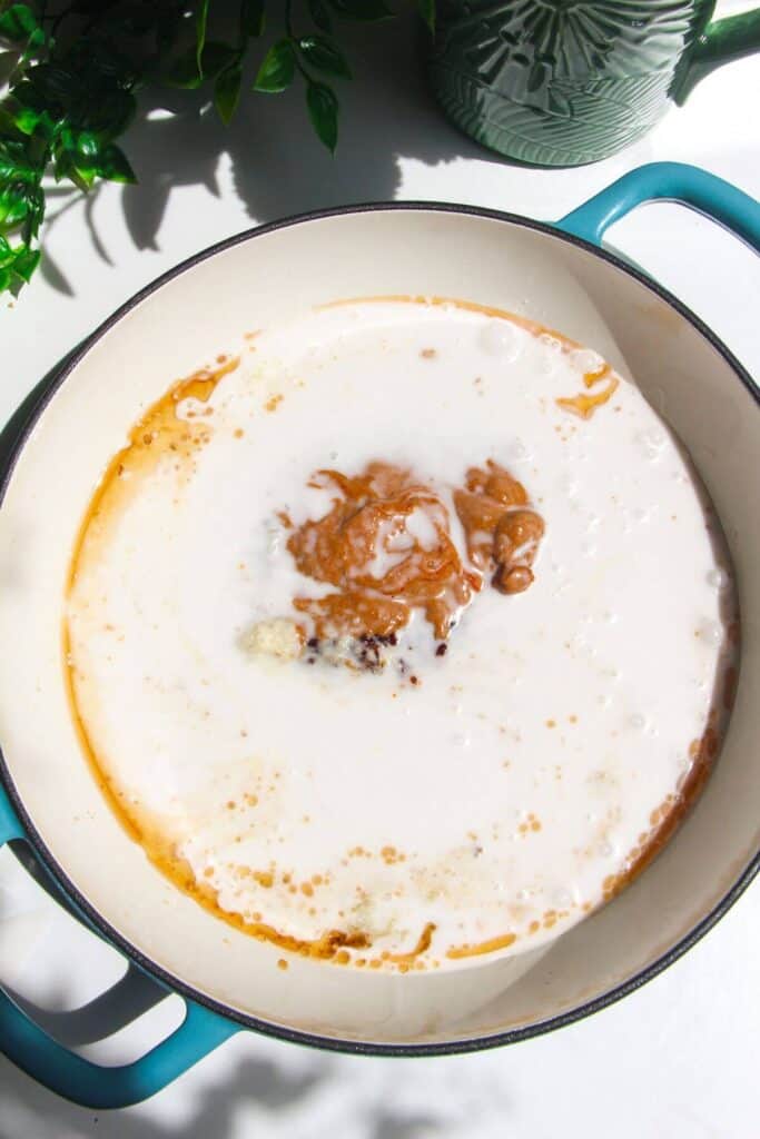 Coconut milk and other sauce ingredients in white skillet.