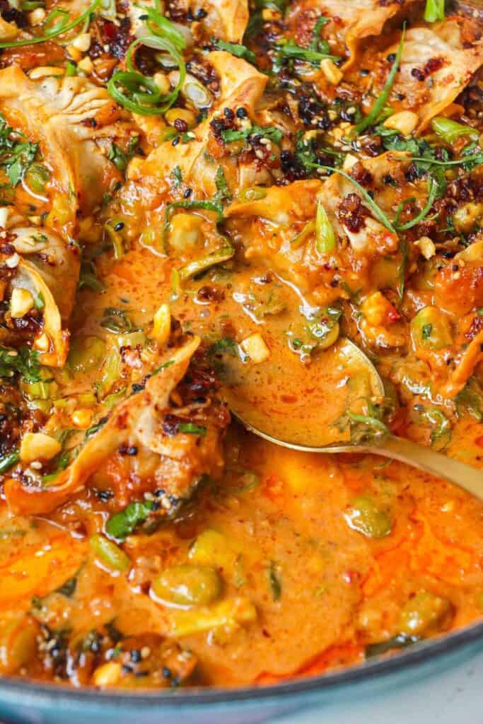 Close up of serving spoon in skillet of baked dumplings.