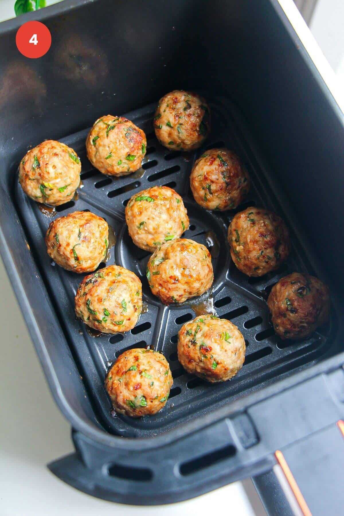 Cooked dumpling meatballs in air fryer basket.