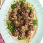 Cheeseburger meatballs on burger sauce on a platter.