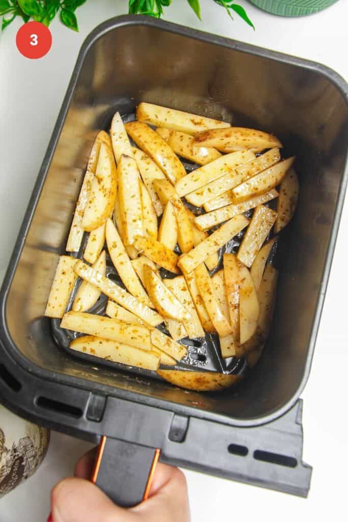 Seasoned fries in air fryer basket.