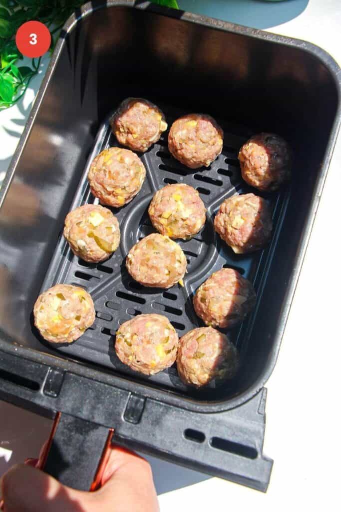 Cheeseburger meatballs in air fryer basket.