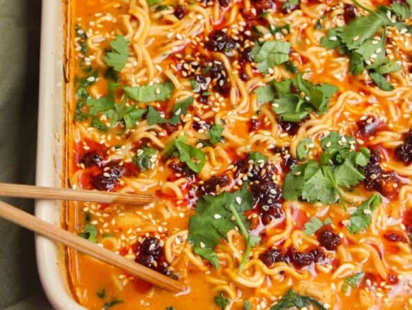 Baked satay ramen in an oven dish, with chopsticks on the side.