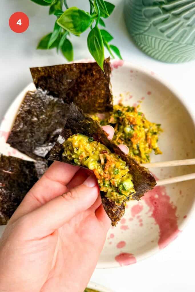 Holding nori sheet filled with chicken salad.