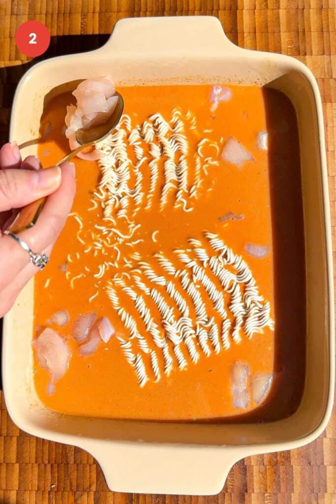 Ramen cakes in satay sauce in an oven dish, with diced chicken.
