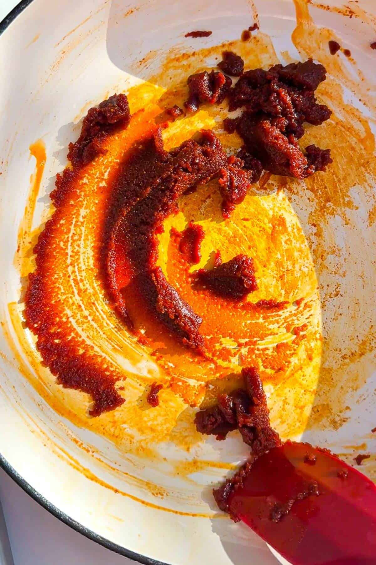 Stirring gochujang paste and peanut butter in a pan.