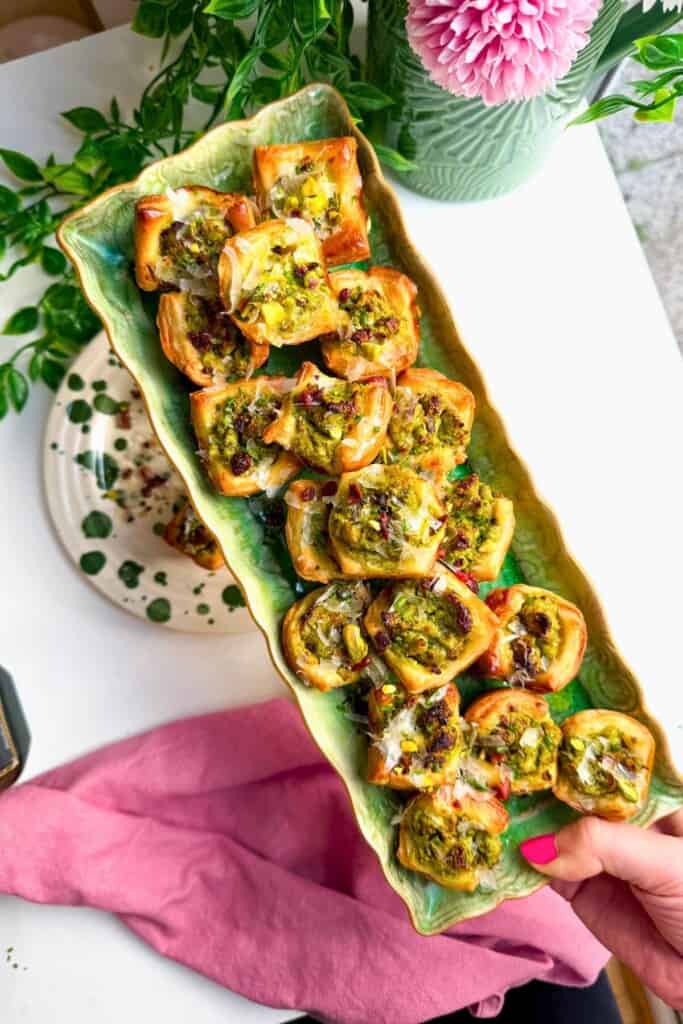 Pesto ricotta puff pastry cups laid out on serving plates.