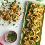 Pesto ricotta puff pastry cups laid out on serving plates.