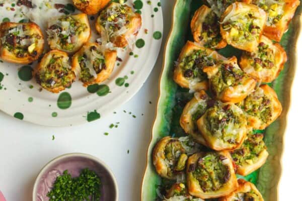 Pesto ricotta puff pastry cups laid out on serving plates.