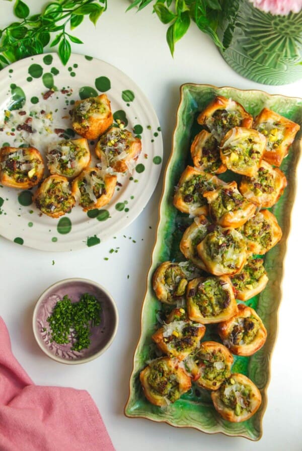 Pesto ricotta puff pastry cups laid out on serving plates.