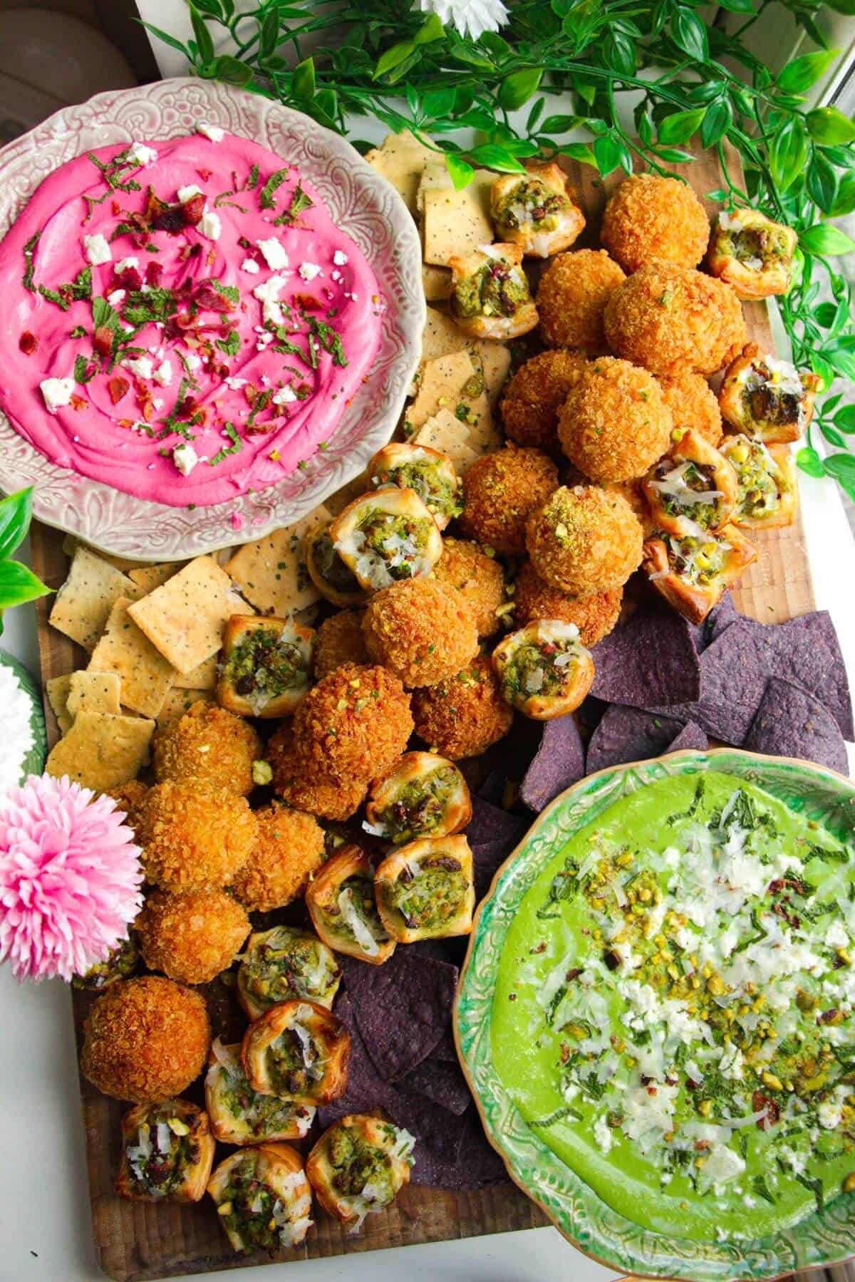 Dips, arancini and puff pastry bites on a wooden board.