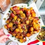 Bacon wrapped tater tots drizzled with honey and nuts on a plate.