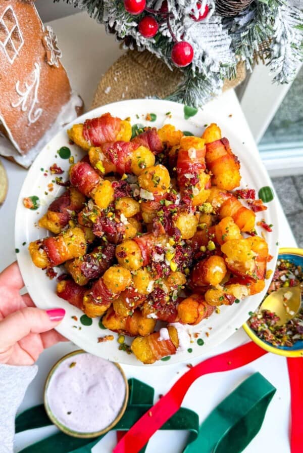 Bacon wrapped tater tots drizzled with honey and nuts on a plate.