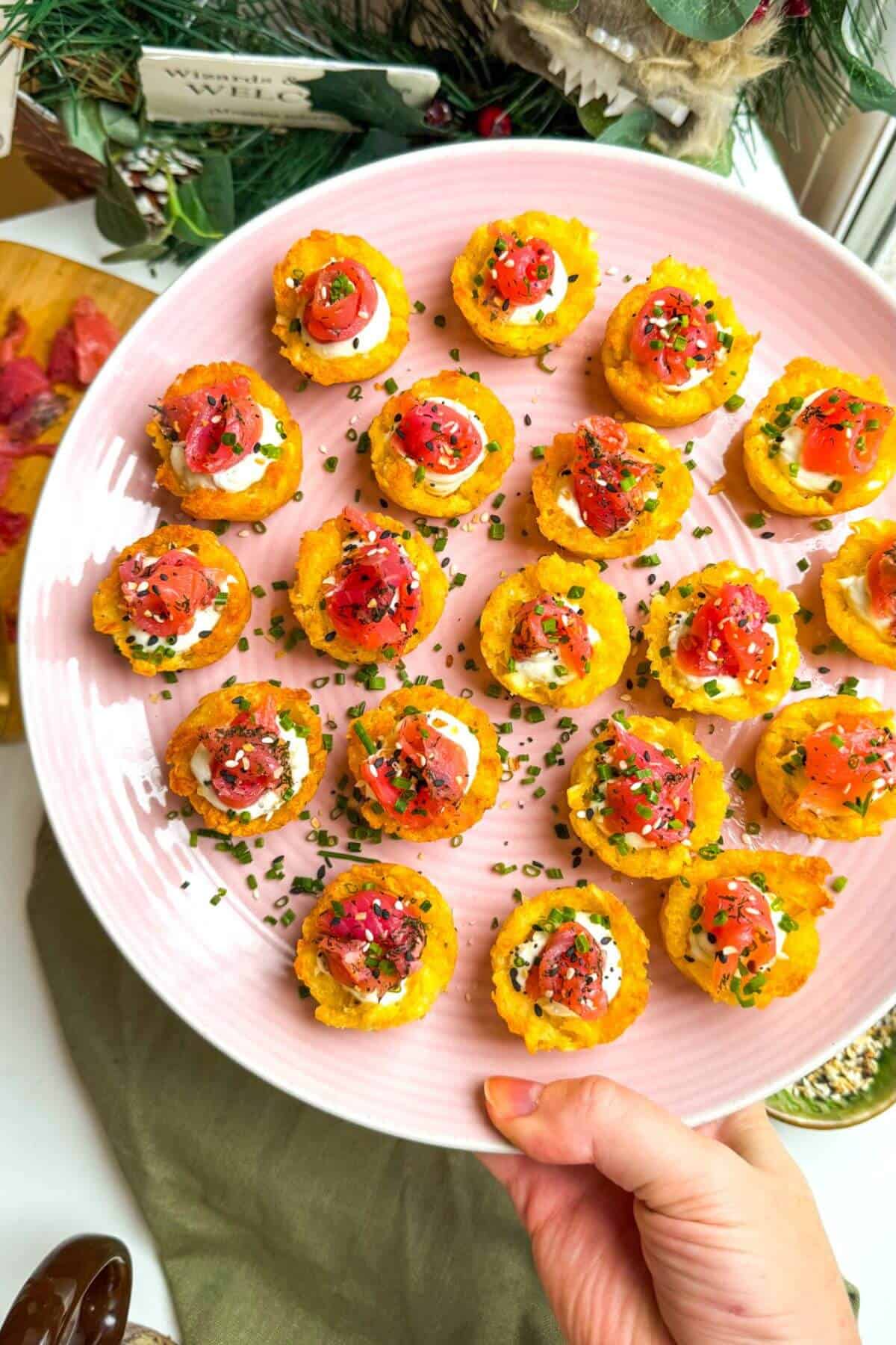Smoked salmon hash brown cups on a platter with everything bagel seasoning on the side.