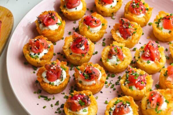 Smoked salmon hash brown cups on a platter with everything bagel seasoning on the side.