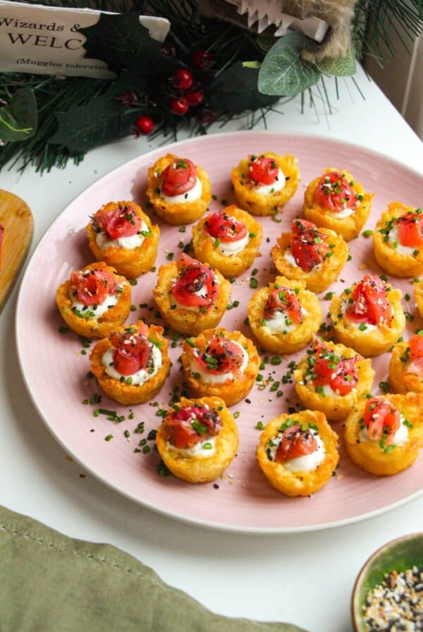 Smoked salmon hash brown cups on a platter with everything bagel seasoning on the side.