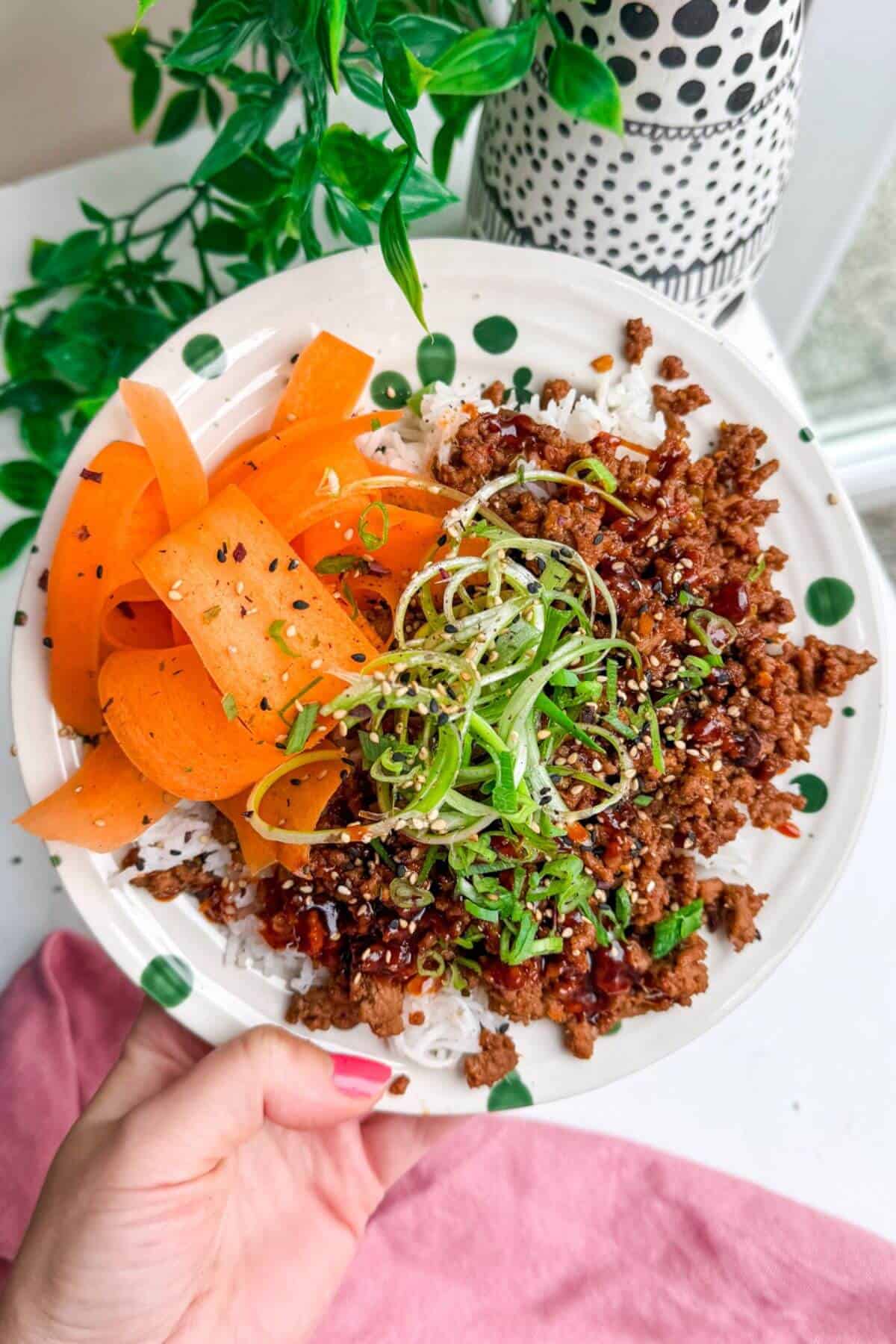 Holding sticky gochujang rice bowl.