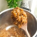 Wooden spoon with caramelized onions, with Instant Pot in the background.