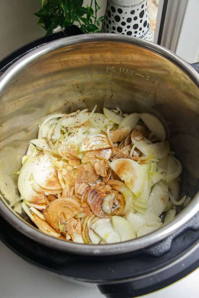 Sliced onions with salt, pepper, olive oil, balsamic vinegar in an Instant Pot.