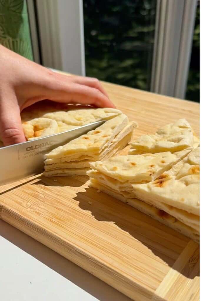 Chopping pita bread into triangles.