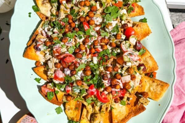 Hand holding platter of Greek pita nachos.