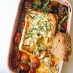 Baked feta tomato dip with bread in the dish.