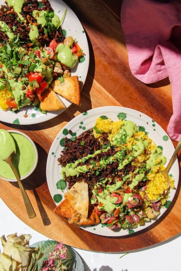 Two Mediterranean beef rice bowls, with green tahini sauce on the side.