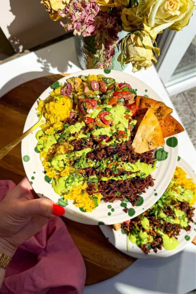 Hand holding up a Mediterranean beef rice bowl.