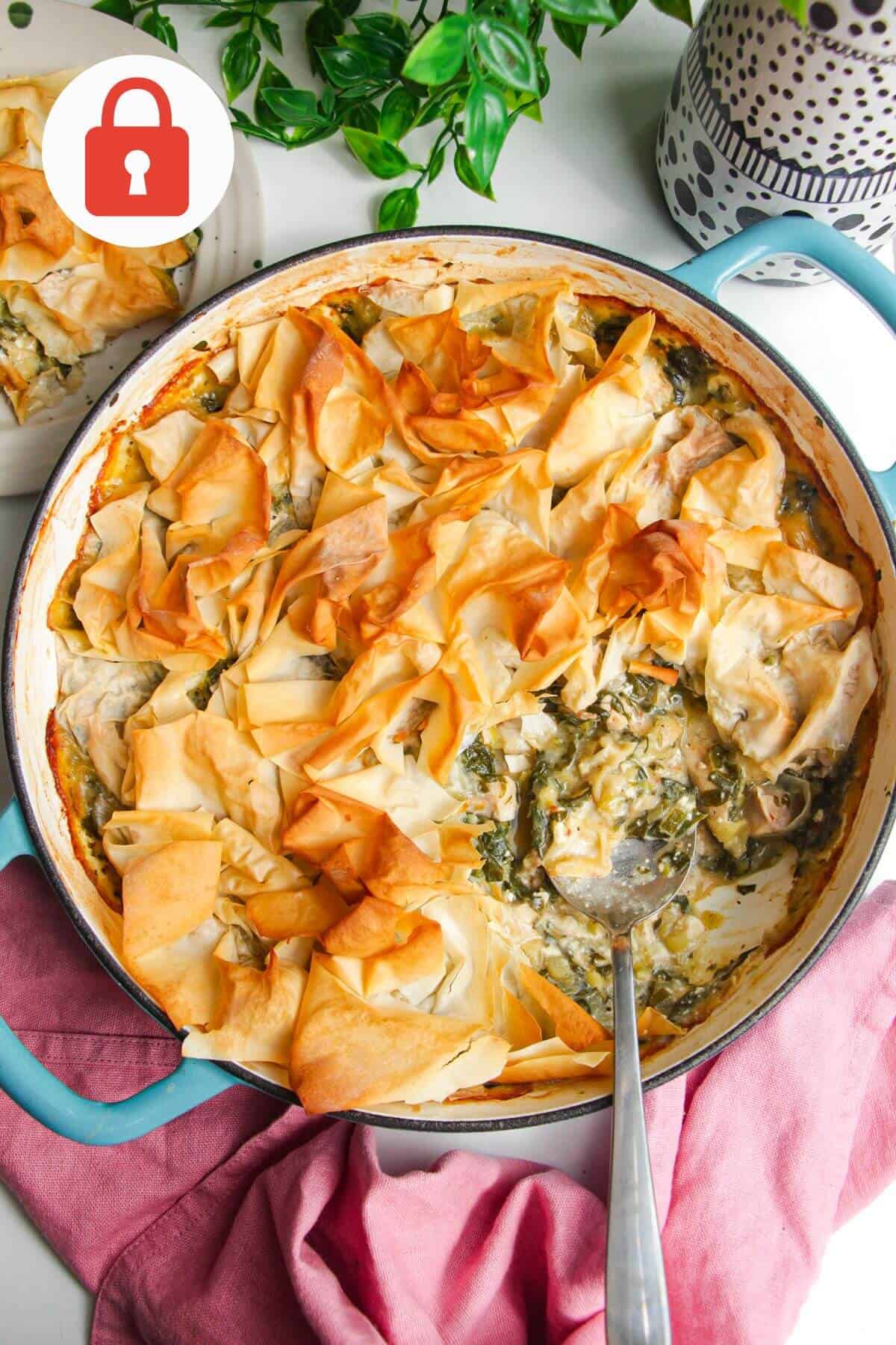 Spanokopita chicken pot pie, with a serving spoon in the pan.