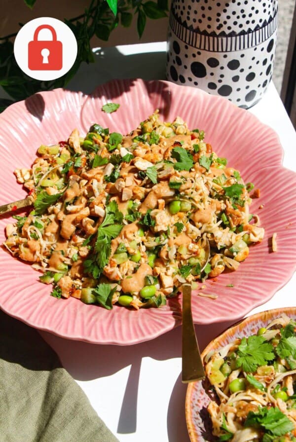 Satay chicken crunch salad in serving bowl with spoon.