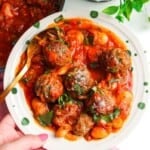 Holding plate with beef meatballs and butter beans in tomato sauce.
