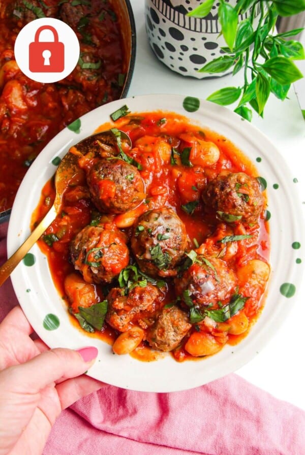 Holding plate with beef meatballs and butter beans in tomato sauce.