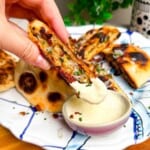 Dipping Caesar stuffed flatbread in Caesar dipping sauce.