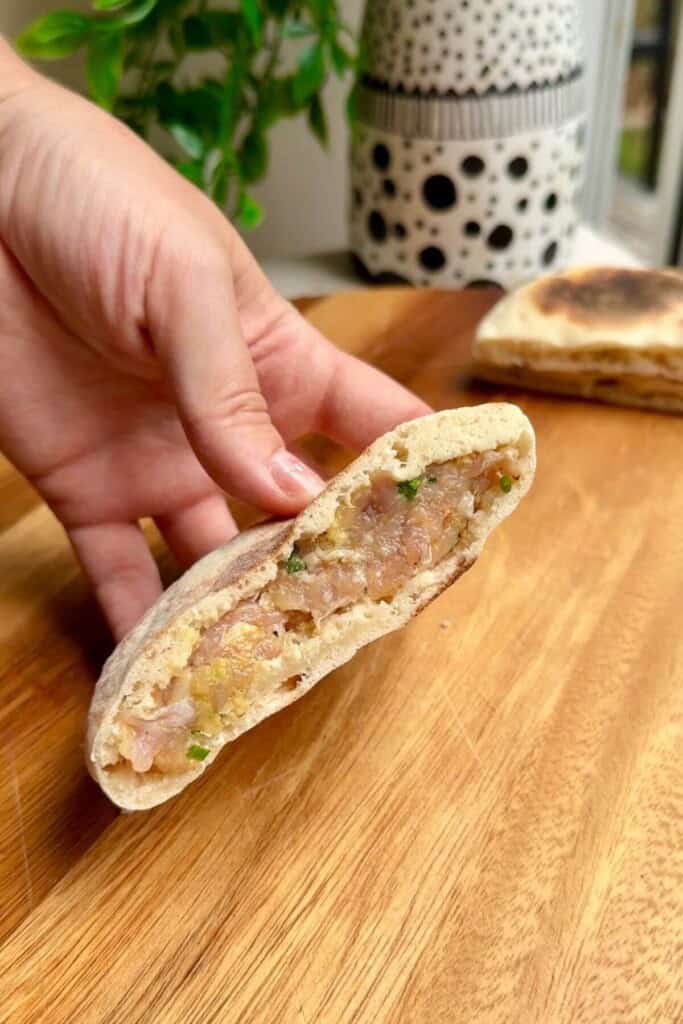 Hand holding stuffed Caesar flatbread.