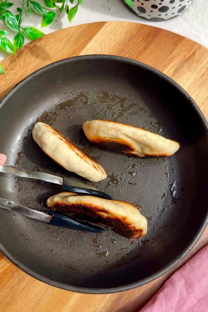 Three flatbreads being seared in a pan.