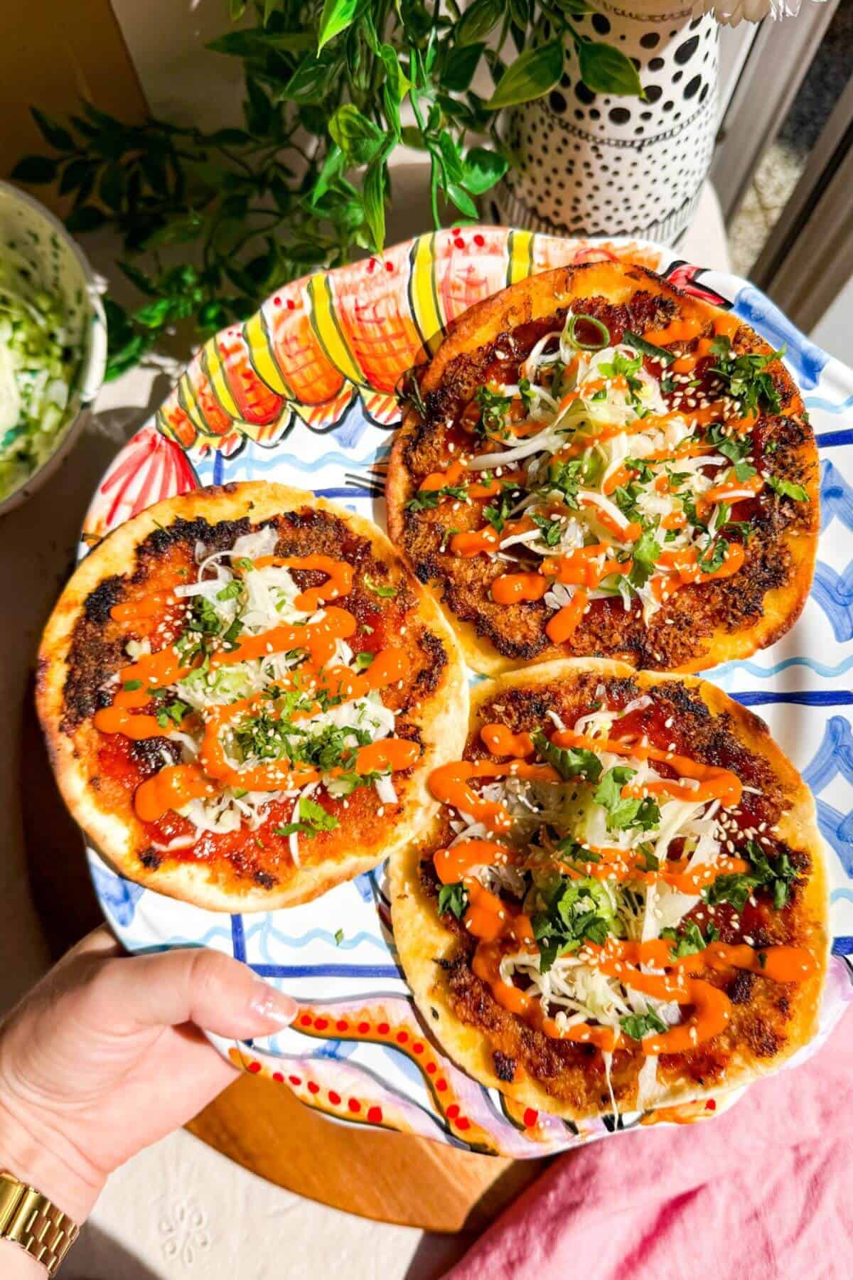 Holding a platter of Korean fried chicken smash tacos.