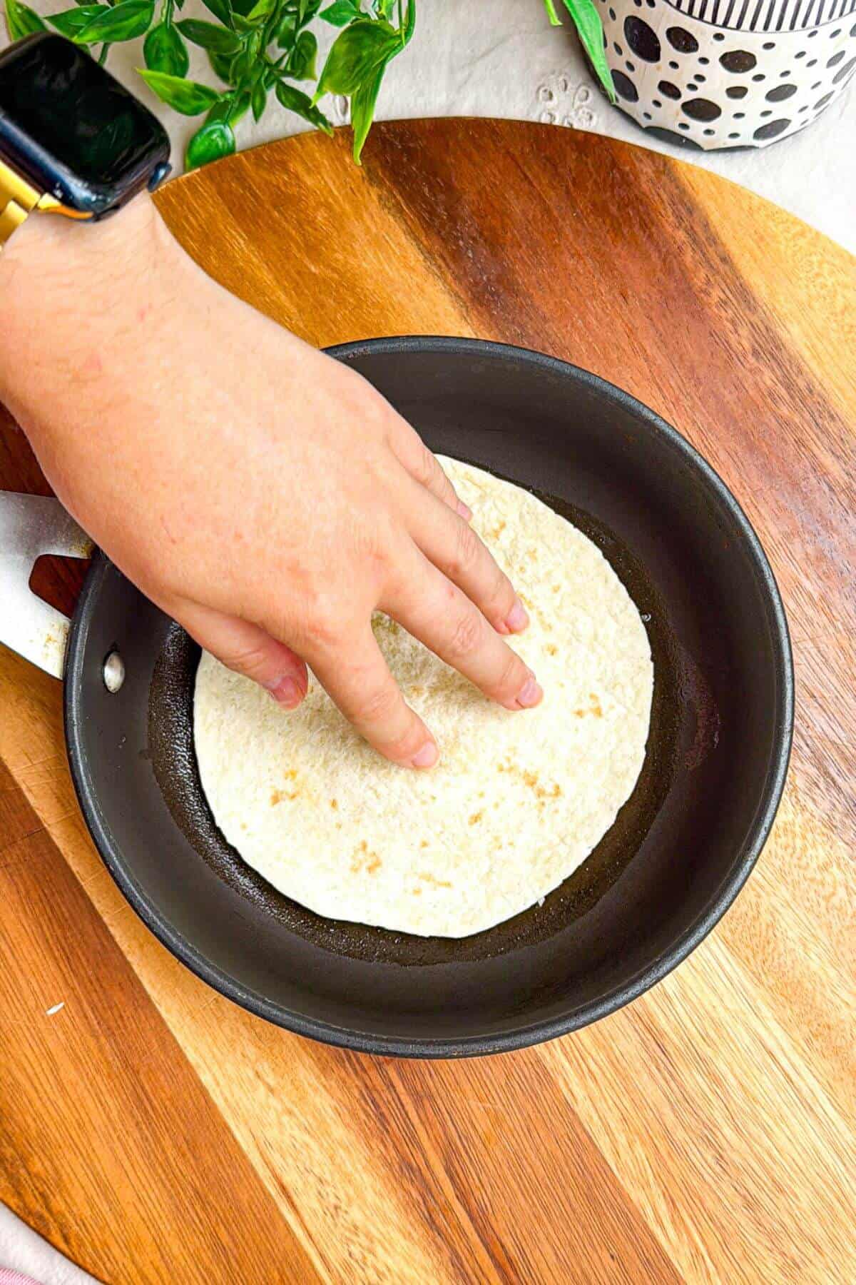 Pressing mini tortilla into a hot pan.