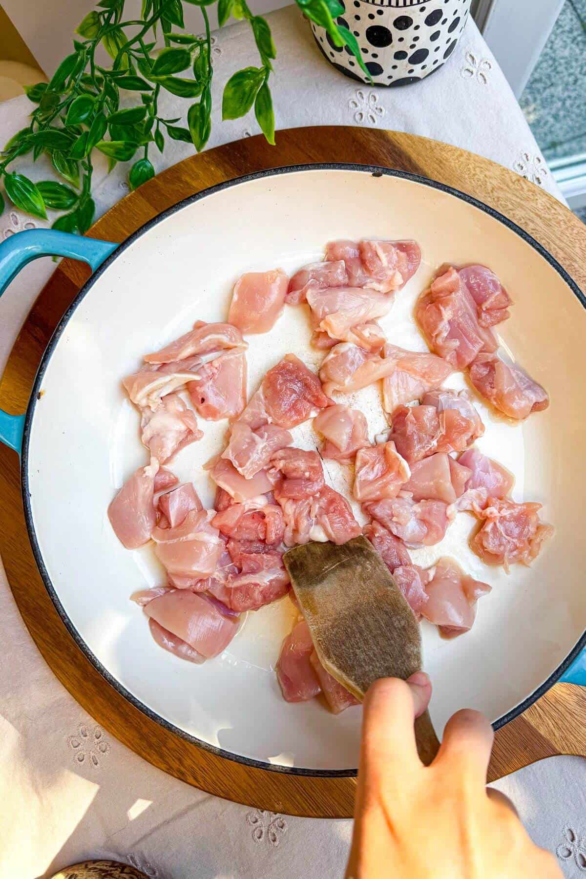 Cooking diced chicken thighs in a pan.