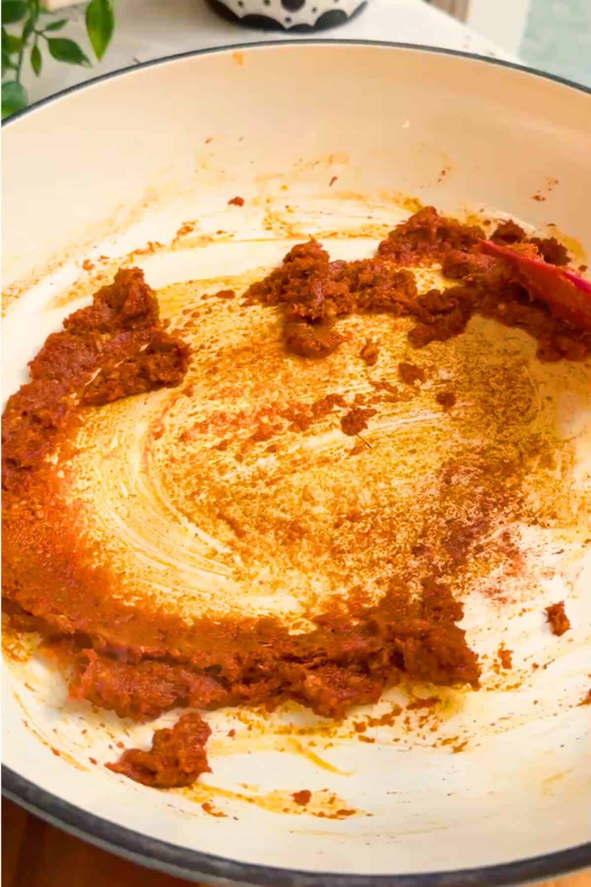 Red curry paste stirred in a pan.