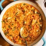Red curry chicken orzo in a pan with a spoon.