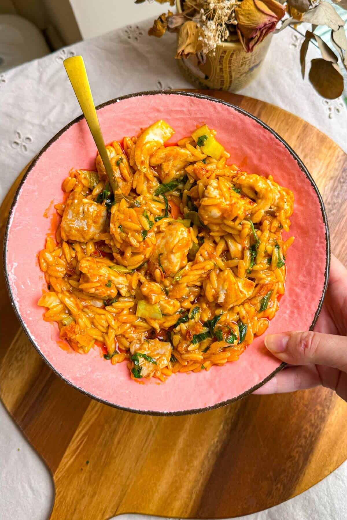 Holding a plate of red curry chicken orzo.