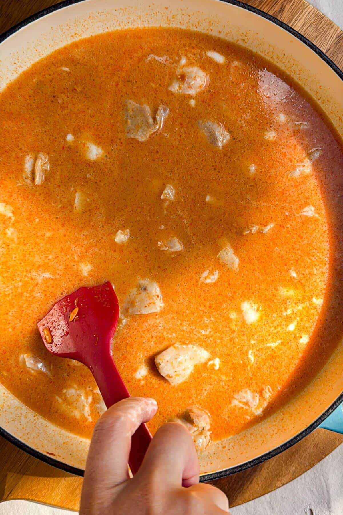 Stirring chicken through stock, coconut milk and orzo.