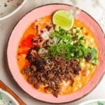 Sticky beef, rice, scallions in a pink bowl with orange gochujang broth.